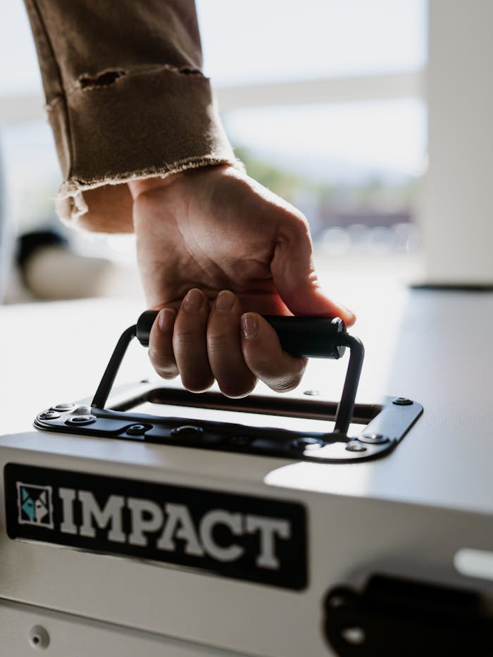 services-05 Close-up of a hand holding the handle of a durable Impact dog crate, emphasizing quality and design.