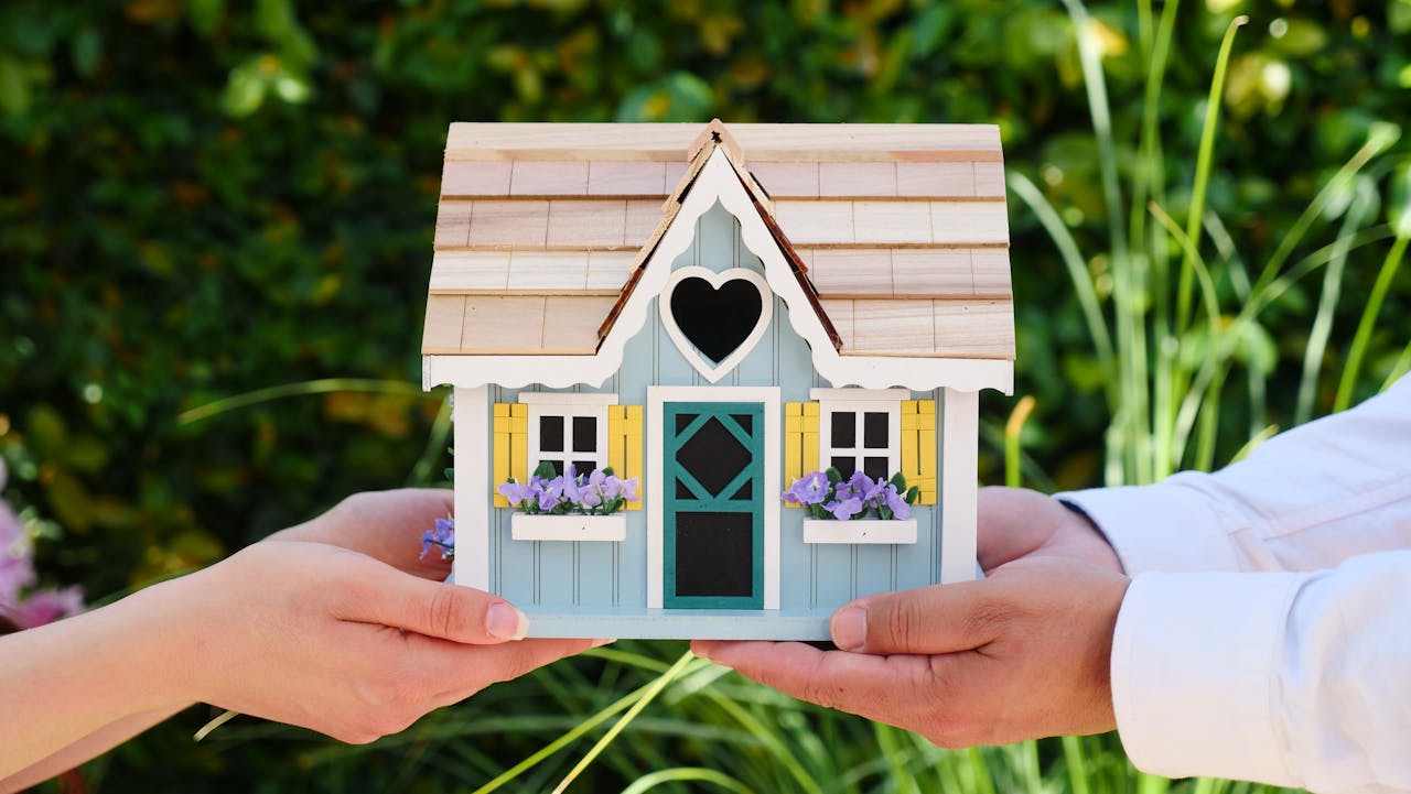 about-us Close-up of hands holding a detailed miniature house model, symbolizing goals of homeownership.